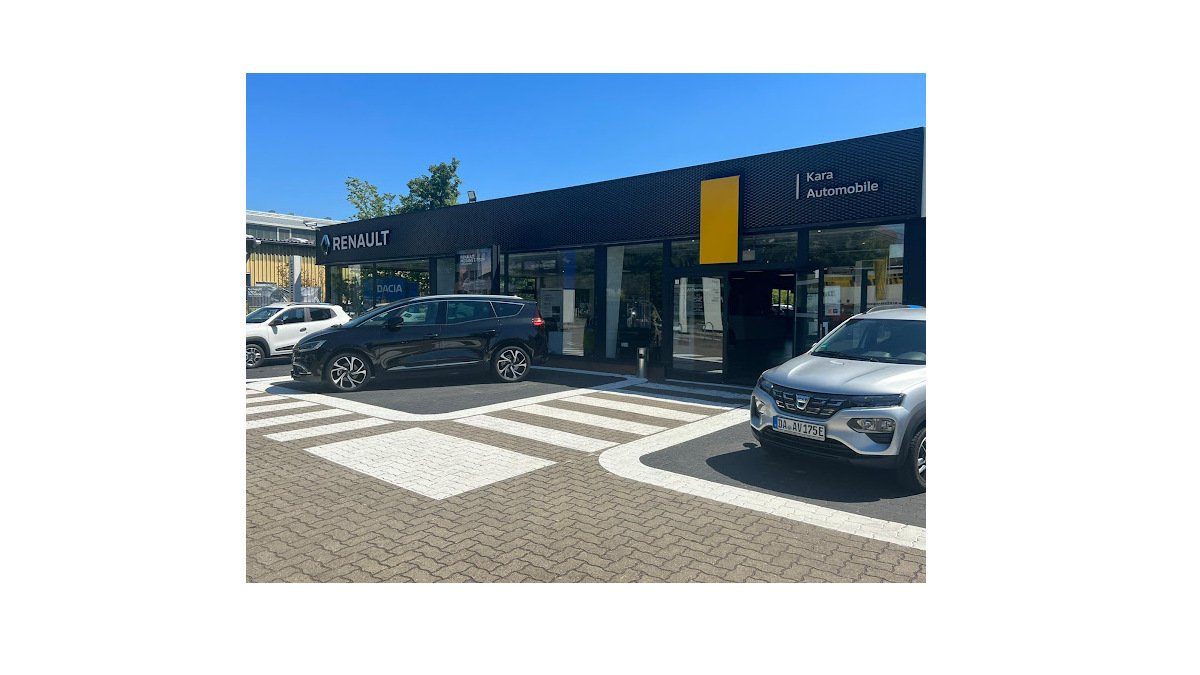Renault Autohaus mit zwei Autos auf dem Parkplatz und klarer blauer Himmel über dem Gebäude.
