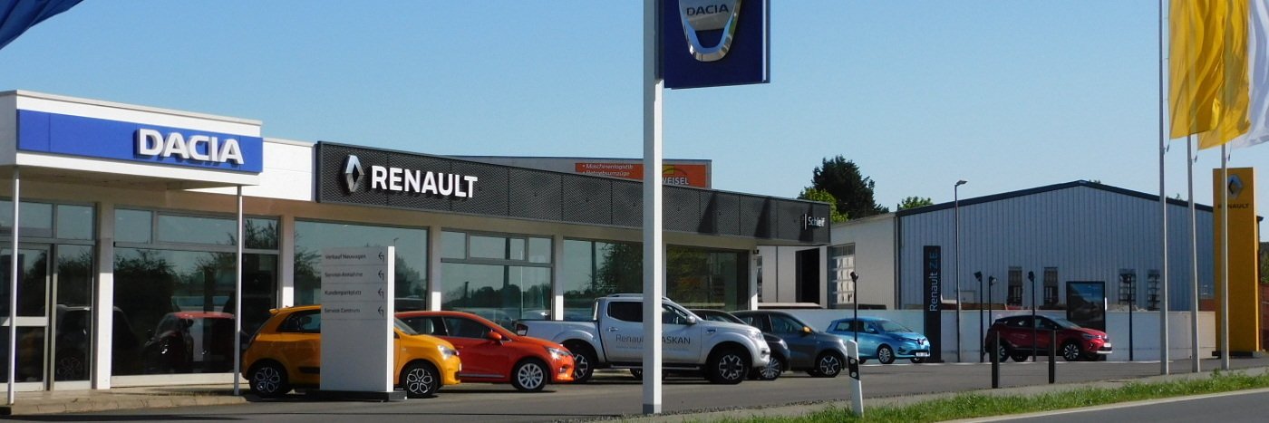 Ausstellung von Dacia und Renault Autos vor einem Autohaus mit verschiedenen Modellen und Flaggen.