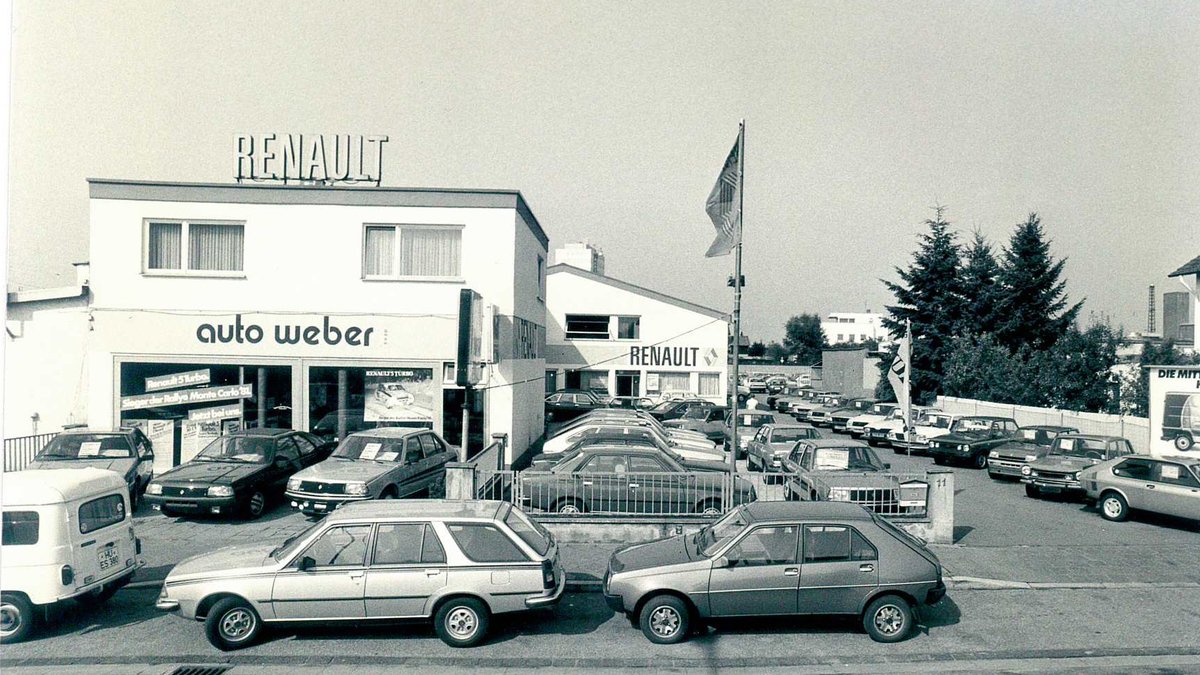 Renault Auto Weber Autohaus mit verschiedenen Autos bei Tageslicht, 80er Jahre Stil.