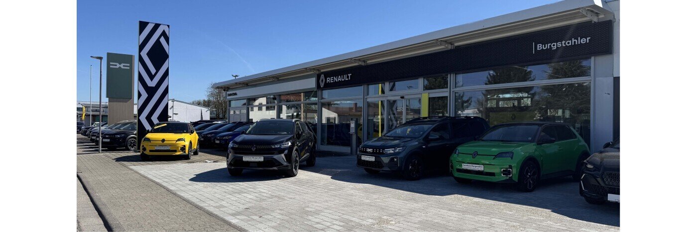 Renault Autohaus Burgstähler mit verschiedenen Fahrzeugen, darunter ein gelbes und ein grünes Auto, bei klarem Wetter.