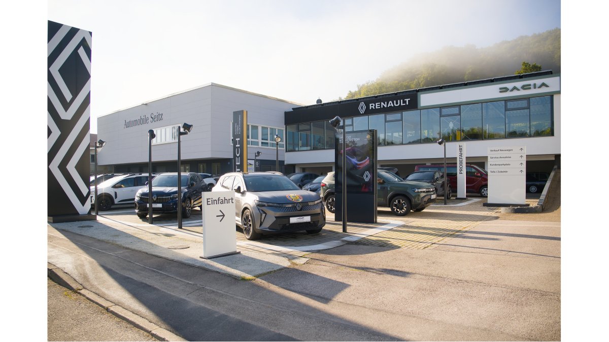 Autohaus mit Renault und Dacia Fahrzeugen auf dem Parkplatz sowie Einfahrtsschild in sonniger Umgebung.