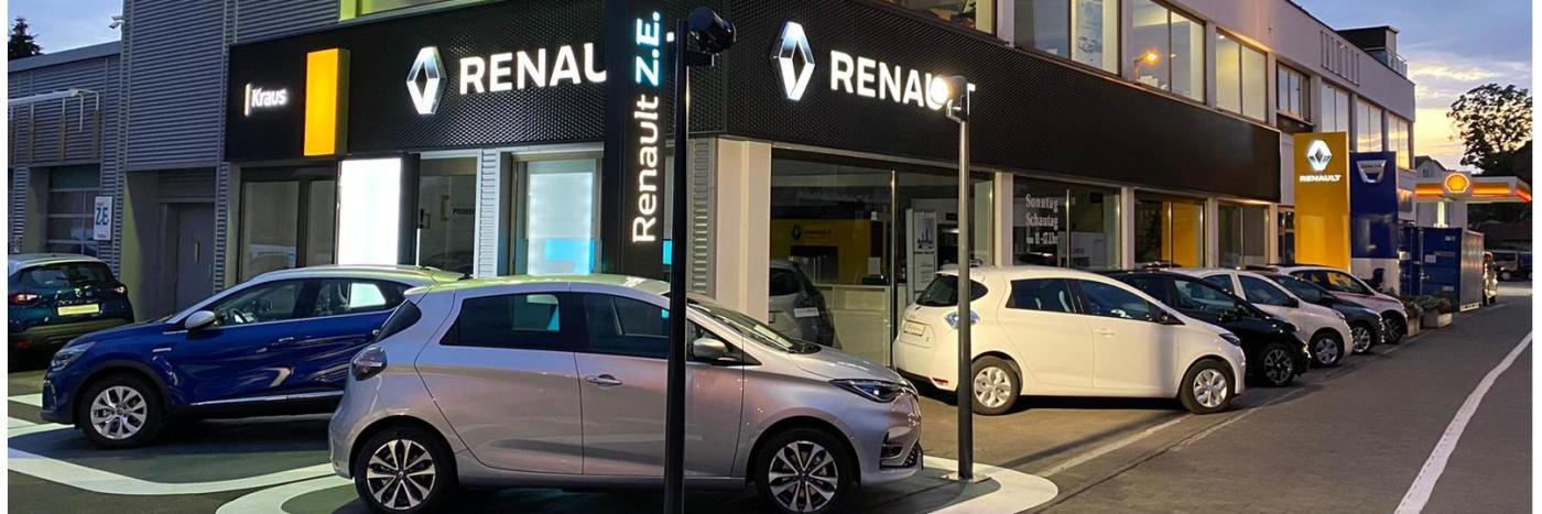 Renault Autohaus mit mehreren Fahrzeugen, erleuchtet bei Dämmerung, Zeichen für Renault Z.E. und andere Marken.