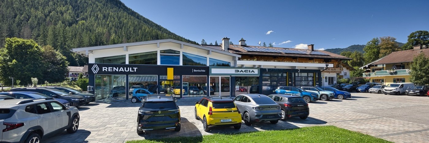 Renault- und Dacia-Autohändler in einer malerischen Berglandschaft mit mehreren Autos auf dem Parkplatz.