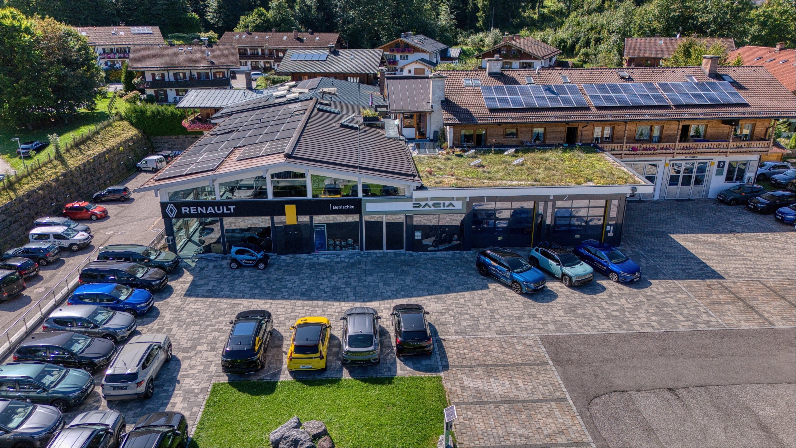 Luftaufnahme eines Renault und Dacia Autohauses mit Parkplätzen und Solarzellen auf den Dächern.