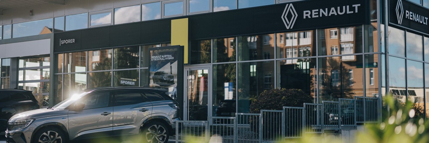 Renault Autohaus mit moderner Glasfront und silbernem SUV auf dem Parkplatz.