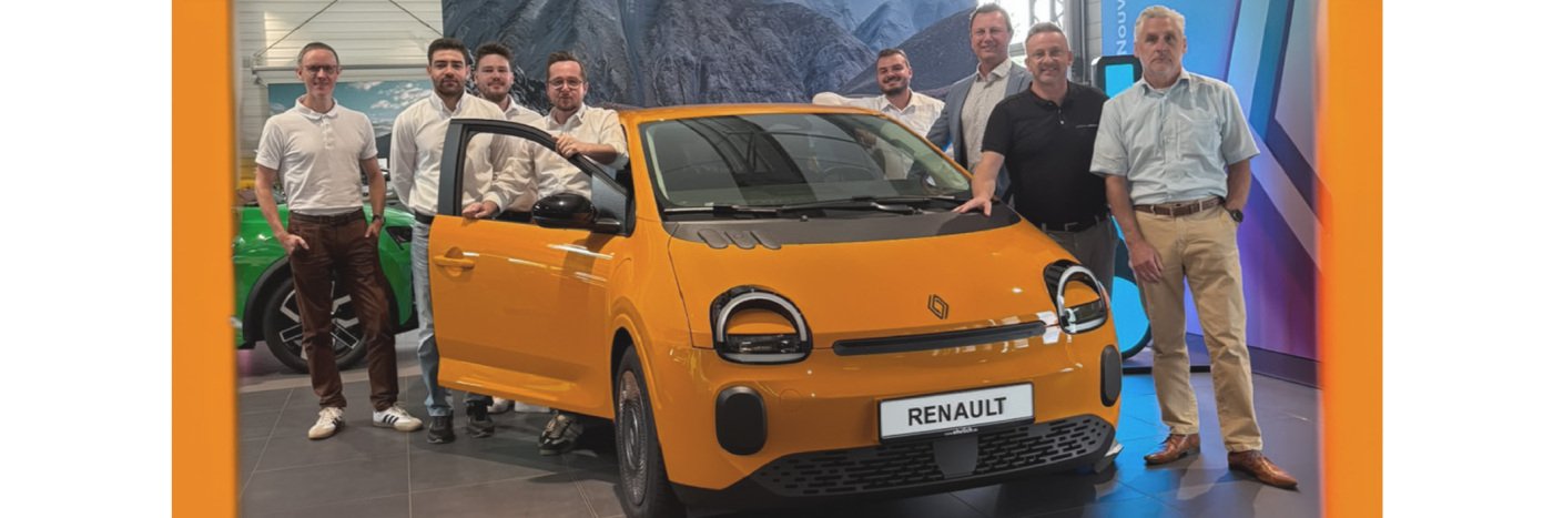 Gruppe von Personen steht neben einem gelben Renault im Ausstellungsraum. Bunte Hintergrundgestaltung.