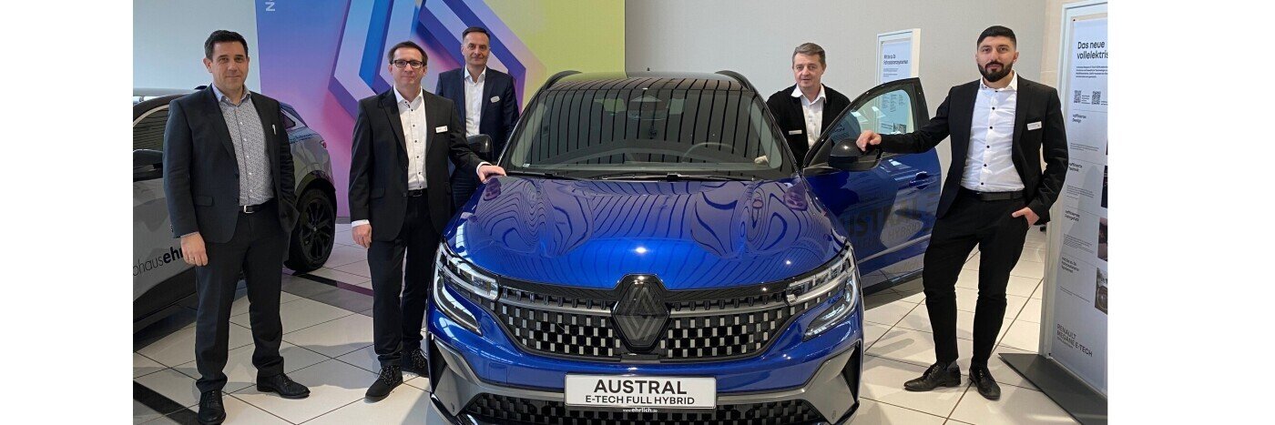 Fünf Personen stehen neben einem blauen Renault Austral E-Tech Plug-in-Hybrid in einem Ausstellungsraum.