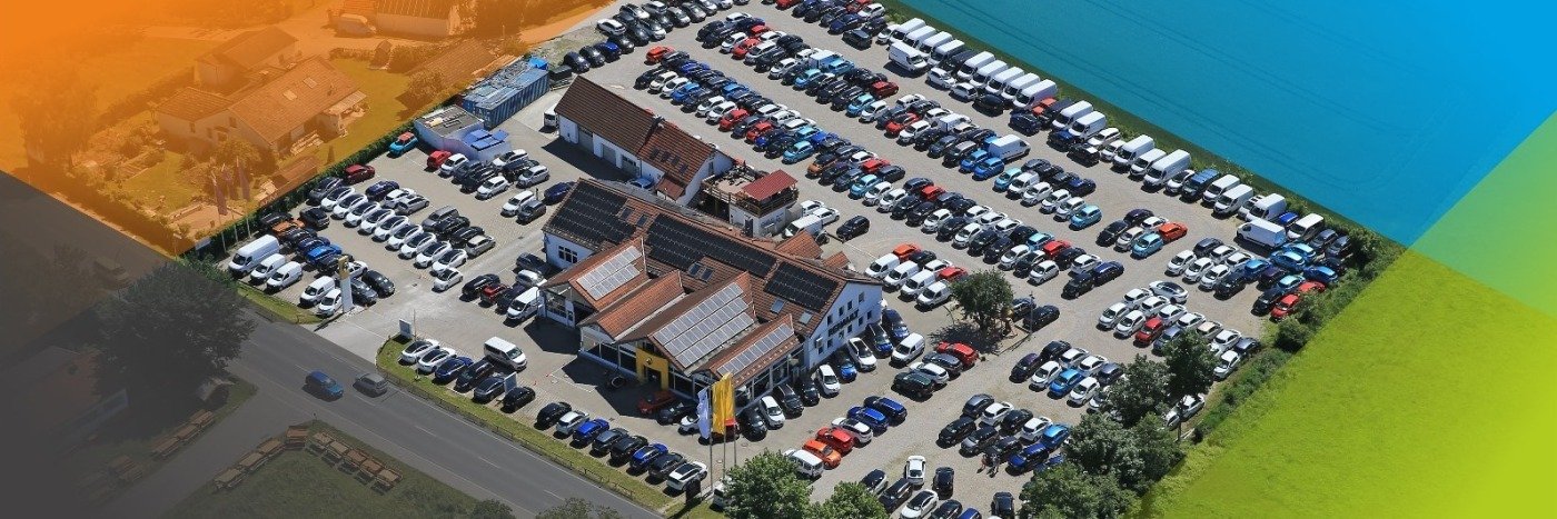 Luftaufnahme von einem großen Parkplatz mit vielen Autos und einem Gebäude im Hintergrund.