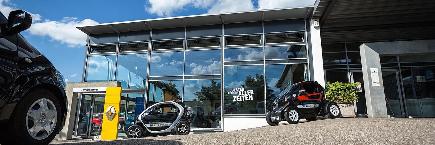 Renault Autohaus mit zwei Autos vor einem großen Glasgebäude an einem sonnigen Tag.