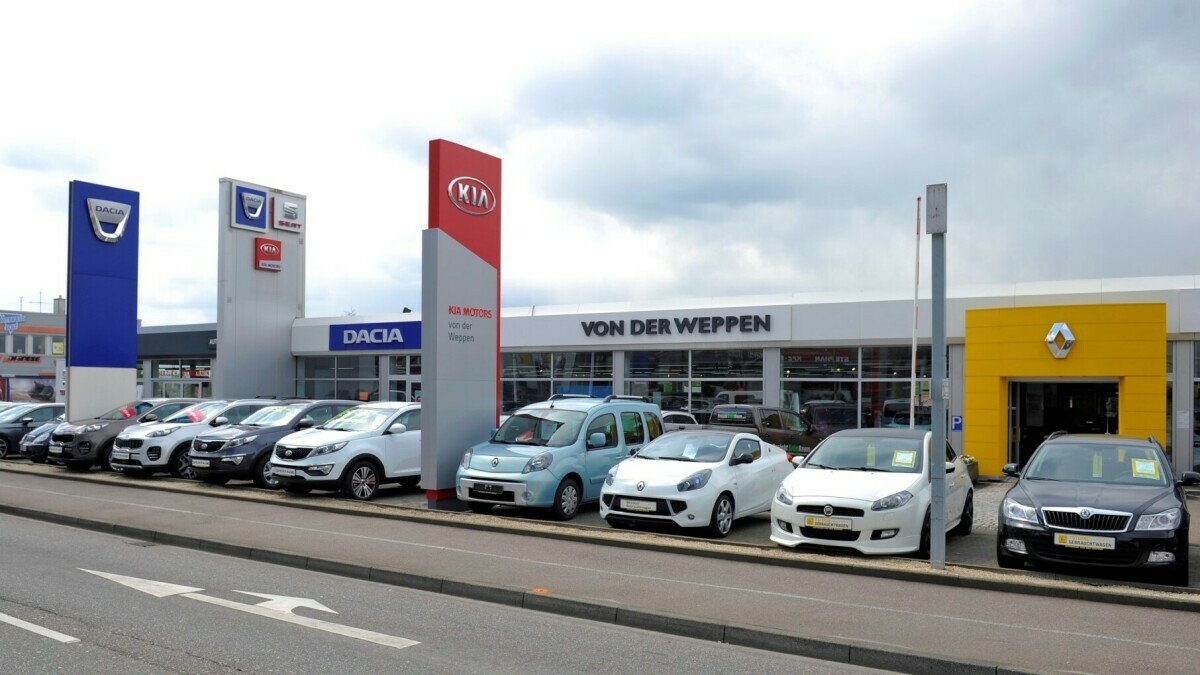 Autohäuser mit verschiedenen Fahrzeugen und Marken wie Dacia, Kia und Renault, auf einer belebten Straße.