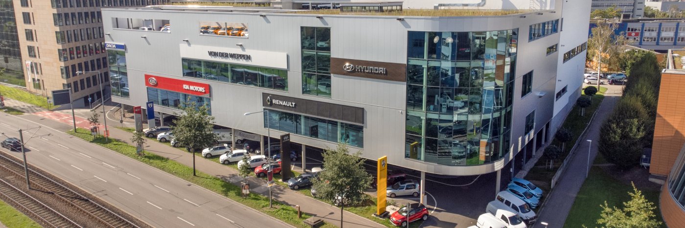 Modern Autohaus mit verschiedenen Marken, darunter Hyundai und Renault, entlang einer Hauptstraße.