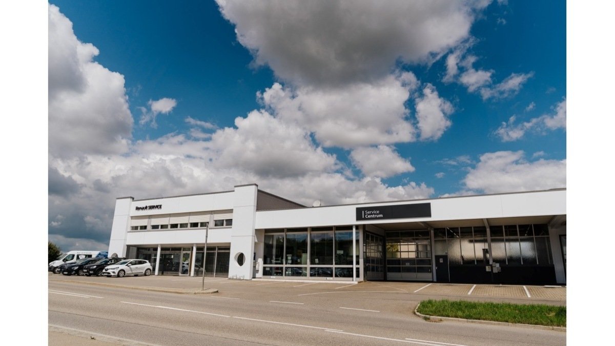 Renault-Service-Center mit moderner Architektur und Fahrzeugen vor einem klaren Himmel.