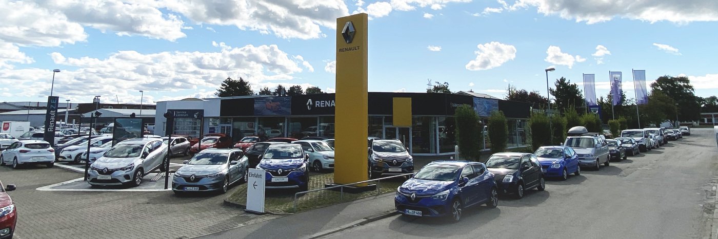 Renault Autohaus mit zahlreichen Autos auf dem Parkplatz und einem großen Werbeschild im Hintergrund.