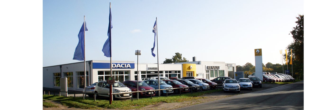 Autohändler mit Dacia und Renault Fahrzeugen auf dem Parkplatz, umgeben von Flaggen.