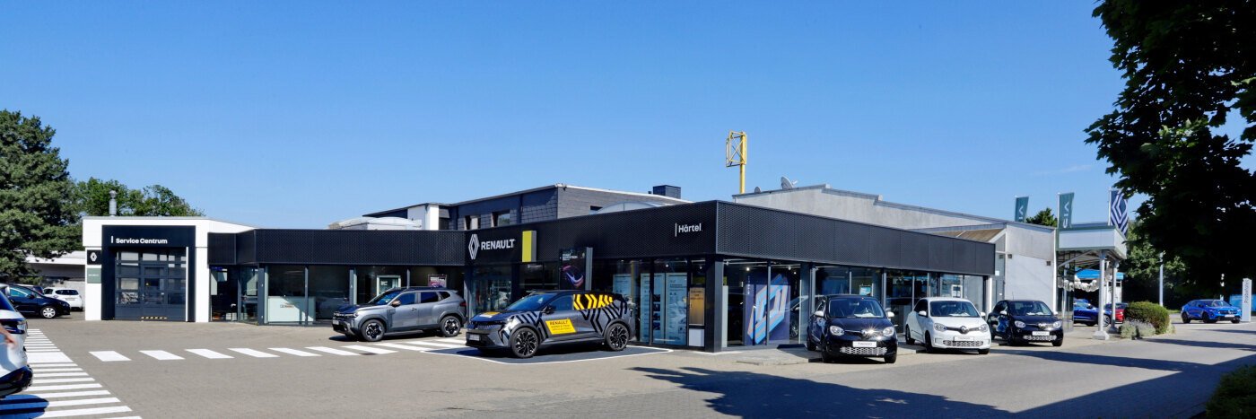 Renault Autohaus mit modernen Fahrzeugen und schönem blauen Himmel im Hintergrund.