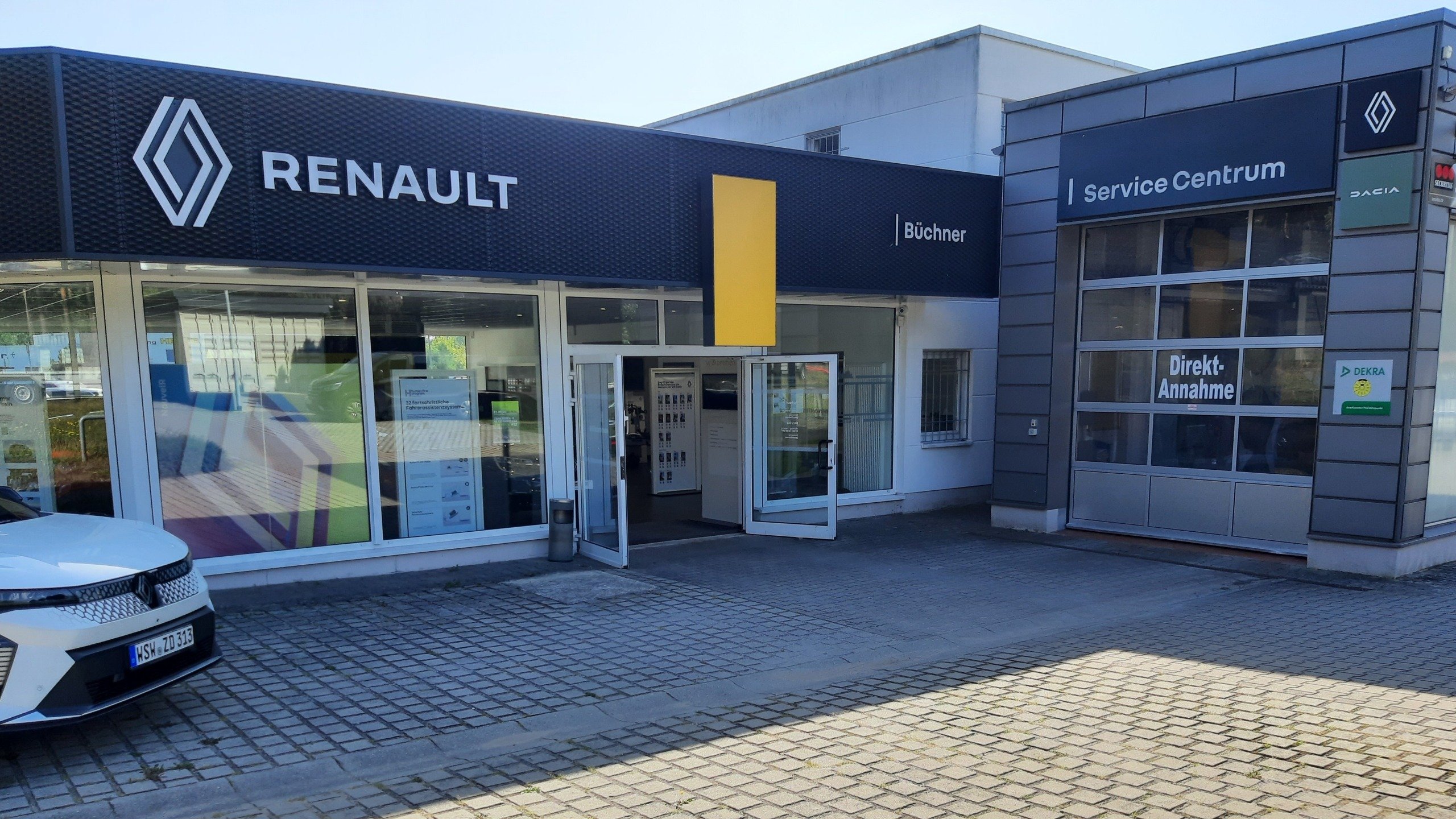 Renault Autohaus mit gelbem Schild und Servicezentrum, Tageslicht, moderne Architektur.