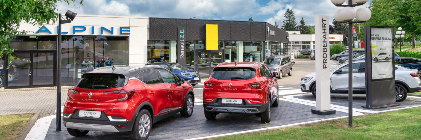 Renault Captur und andere Modelle vor dem Autohaus Alpine, Werbeschilder sichtbar.