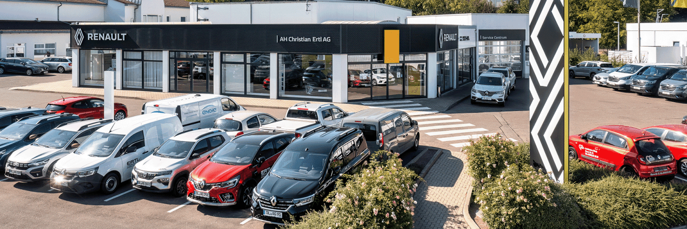 Renault Autohaus mit mehreren Fahrzeugen auf dem Parkplatz, das Gebäude zeigt große Fenster und die Marke Renault.