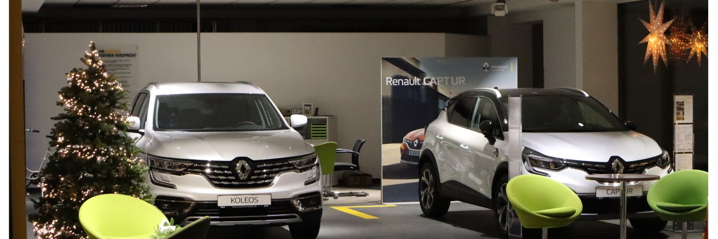 Zwei Renault Fahrzeuge, Koleos und Captur, in einem Ausstellungsraum mit einem Weihnachtsbaum.